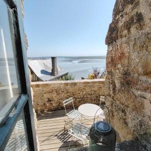 a balcony with a table and chairs and the ocean at Chez Adèle in Le Mont Saint Michel