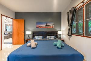 a bedroom with a large blue bed with pillows at Coastline Pearl Holiday Home, Bangtao Beach in Ban Thalat Choeng Thale