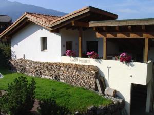 a white house with a stone fence and flowers at Casa Migiur 3,5 Zimmer-Apartment in Laax