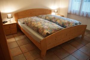 a wooden bed in a bedroom with two lamps on a table at Casa Migiur 3,5 Zimmer-Apartment in Laax