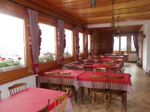 a restaurant with red tables and chairs and windows at Hôtel les skieurs in Bellevaux