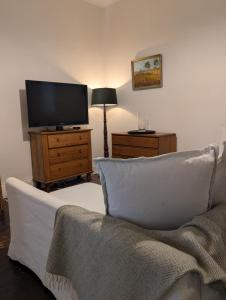 a living room with a couch and a flat screen tv at Your CBD Treetop Base | Parking, Wifi & Views in Kings Park