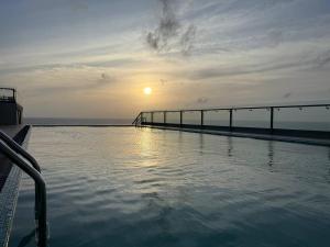 a swimming pool with the sun setting over the ocean at High Tides End Ceylon Negombo in Negombo