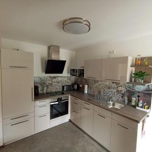 a kitchen with white cabinets and stainless steel appliances at Ferienwohnung mit Blick auf die Moselloreley in Piesport