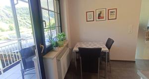 a dining room with a table and chairs and a balcony at Ferienwohnung mit Blick auf die Moselloreley in Piesport