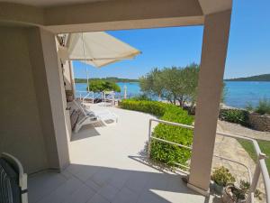 a porch with an umbrella and a view of the water at Apartmani Sandra i Davor Lonic in Kukljica