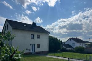una casa bianca con cielo azzurro e nuvole di Ferienwohnung für 6 Personen - 3 Schlafzimmer - Dachgeschoss a Holzappel