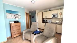 a living room with two chairs and a kitchen at Strandburg, das smarte Penthouse in ÜckeRitz mit PKW Stellplatz! in Ueckeritz
