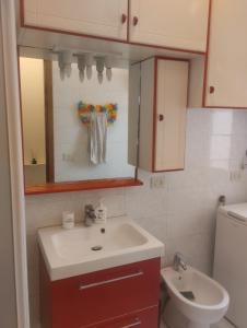 Un baño con lavabo, inodoro y espejo. en Ninfea, en Pescara