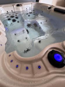 a bath tub filled with water with blue buttons at LA MAISON DE CECILE jusqu'à 6 personnes en Normandie in Condé-sur-Vire