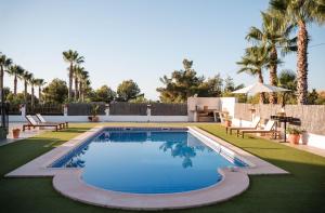 a swimming pool with chairs and palm trees in a yard at La casa Zamora in Totana