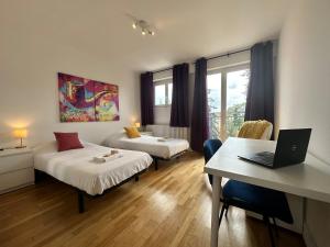 a room with two beds and a desk with a laptop at M Lorry Pop Art 3 chambres avec balcons proche Metz in Metz