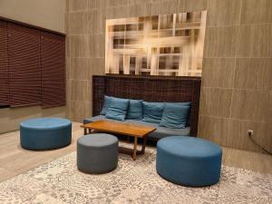 a living room with a couch and two blue stools at Wonderful Geo Bukit Rimau Condominium in Shah Alam