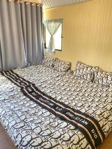 a large bed with a black and white comforter at Homestay Ngỏ Nhỏ in Da Lat