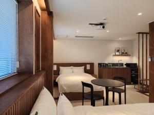 a hotel room with a bed and a table and chairs at Gangneung All Stave Hotel in Gangneung