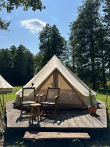 a tent with two chairs and a table in front of it at Glamp Juodis in Ubiškės +25 photos