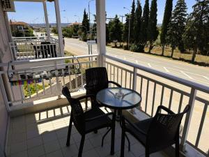 un balcone con tre sedie e un tavolo e una strada di Athitos cozy Studios ad Áfitos