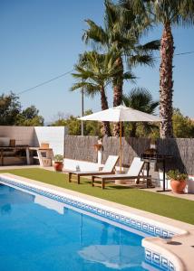 a pool with chairs and an umbrella and palm trees at Apartment La casa Zamora in Totana