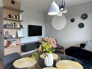 Una sala de estar con un jarrón de flores sobre una mesa. en APARTAMENTY Wakacyjna 53 Dziwnówek, Wrzosowo, en Dziwnówek