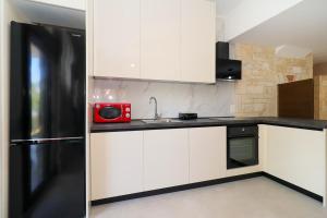 a kitchen with white cabinets and a red microwave at Villa Mykeli in Kriopigi