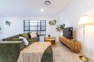 a living room with a couch and a tv at Canopy House Greenbank - Brand New Home in Natures Arms in Greenbank