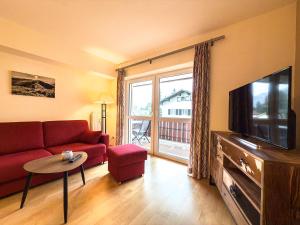 a living room with a red couch and a tv at Alm Loge in Oberstaufen