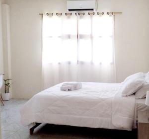 a bedroom with a white bed with a window at Casa Playa Los Marinos in Puerto Baquerizo Moreno