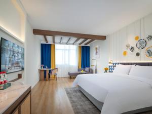 a hotel room with a large white bed and a desk at Ou Xia Mediterranean Hotel, Hyatt Plaza Zhangzhou Changtai in Changtai +13 photos
