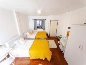 a room with three beds with yellow blankets at Warm House CNX ใกล้นิมมาน เมญ่า สันติธรรม in Chiang Mai