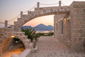 a stone bridge over a walkway with a mountain in the background at Milo Stone Villas in Zefiría