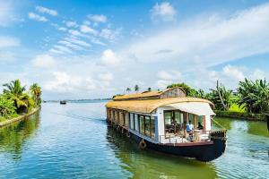 a boat with a roof on a river at Alleppey Haven 6BR Whole House by Backwater in Alleppey
