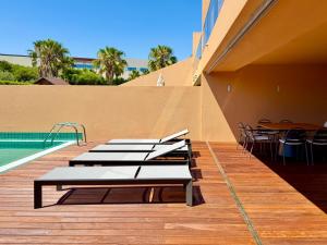 Una hilera de camas en una terraza junto a una piscina. en Salgados Premium Beach Villa 4 Suites, en Guia