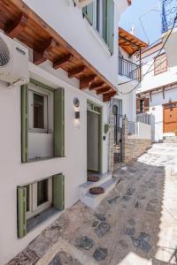 a building with white walls and green doors at Maritina Skopelos Maisonette in Skopelos Town