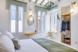 a bedroom with a bed with windows and a mirror at Maritina Skopelos Maisonette in Skopelos Town
