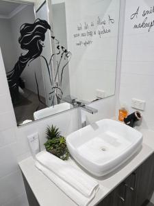 a white bathroom with a sink and a mirror at Stylish 2-Bedroom Apartment in Maddington, 15 Minutes from Perth Airport in Perth