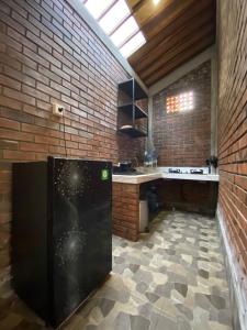 a kitchen with a black refrigerator and a brick wall at Kamanaya Ubud in Ubud