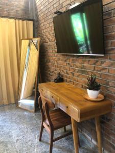 a television on a brick wall with a wooden table at Kamanaya Ubud in Ubud