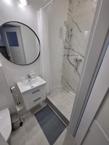 a bathroom with a shower and a sink and a mirror at Apartament Centrum in Gdynia