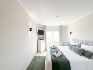 ein weißes Schlafzimmer mit einem großen Bett und einem grünen Teppich in der Unterkunft Apartment Vila Marachique Sunlime Stay in Alvor + 49 Fotos