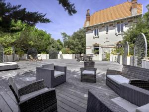 a patio with wicker chairs and tables in front of a house at Villa Familiale près du Moulleau et Plage des Arbousiers avec Grand Jardin et Terrasse - FR-1-433-18 in Arcachon