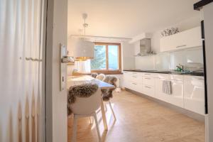 a kitchen with white cabinets and a table and chairs at Marlenca 2 by Arosa Vacations, Familienwohnung mit Bergblick in der Nähe des Skilift-Kulm in Arosa