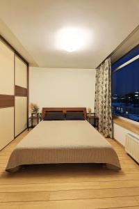 a bedroom with a large bed and a large window at Panorama Apartment Balcony Work Castle View in Vilnius