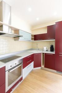 a kitchen with red cabinets and a sink at Panorama Apartment Balcony Work Castle View in Vilnius