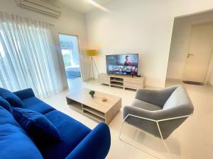 a living room with a blue couch and a tv at Luxury Cozy Apartment - Fairway Galle in Galle