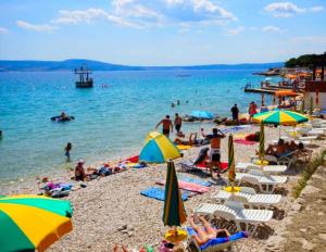 a group of people on a beach with umbrellas at Apartment Di Novi Vinodolski in Novi Vinodolski