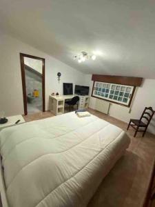 ビーゴにあるÁtico con vistas y aparcamiento gratuitoの大きな白いベッドと机のある寝室