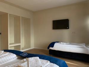 a room with two beds and a flat screen tv at Haven Hotel - Wuppertal in Wuppertal