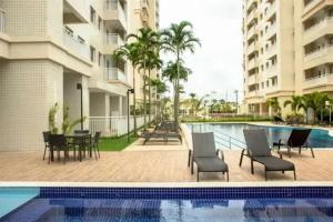 a swimming pool with chairs and a table next to a building at COP 30 Apartamento Luxo - 3 Quartos, Piscina, Academia, Area de Lazer in Belém