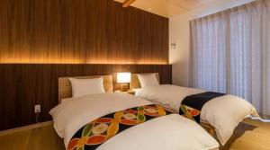 two beds in a hotel room with a window at CoCo Town Goryu in Hakuba