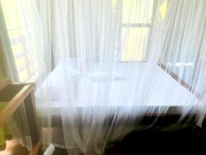 a bed with white curtains in front of a window at Lake Wind Resort & Restaurant in Polgahawelana